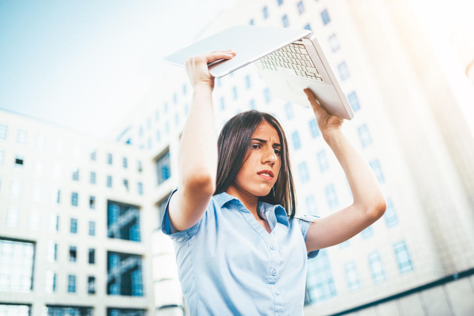 An furious business woman gets bad news and wants to throw a laptop.