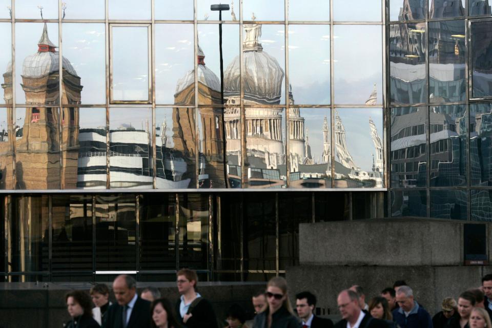 City workers walk past a reflection of St. Paul's Cathedral, top center, as they cross London Bridge heading into the City of London, Friday, Oct. 10, 2008. The FTSE 100 index of leading British shares plunged 7.1 percent in the first half hour of trading on the London Stock Exchange Friday morning, tracking steep declines in Europe, Asia and the U.S.(AP Photo/Sang Tan)