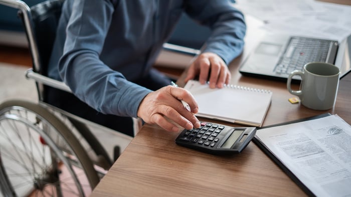 Person in wheelchair using calculator.