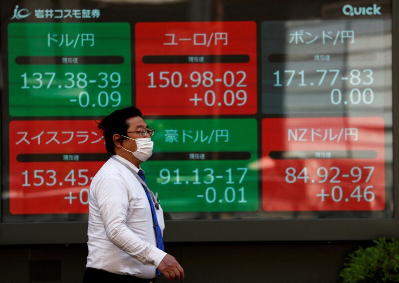 A man walks past an electric monitor displaying the Japanese yen exchange rate against the U.S. dollar, Euro and other foreign currencies outside a brokerage in Tokyo