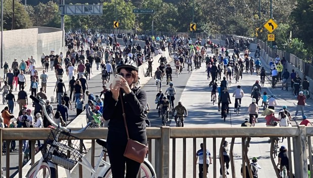 People on foot and bicycles enjoy Arroyo Fest and the use a closed portion of the 110 Freeway at Ave. 52 to walk and bike on Sunday, Oct. 29, 2023. A woman looks at her selfie with the crowd behind her. (Photo by Dean Musgrove, Los Angeles Daily News/SCNG)