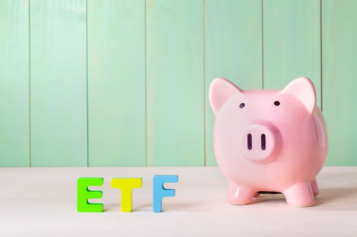 A piggybank next to wooden blocks that spell ETF for exchange-traded fund.