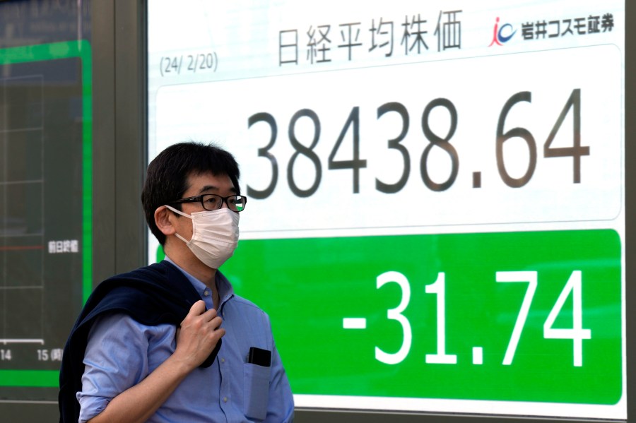 A person walks in front of an electronic stock board showing Japan's Nikkei index at a securities firm Tuesday, Feb. 20, 2024, in Tokyo. Asian shares were trading mixed Tuesday a day after Chinese markets reopened from a long Lunar New Year holiday. (AP Photo/Eugene Hoshiko)