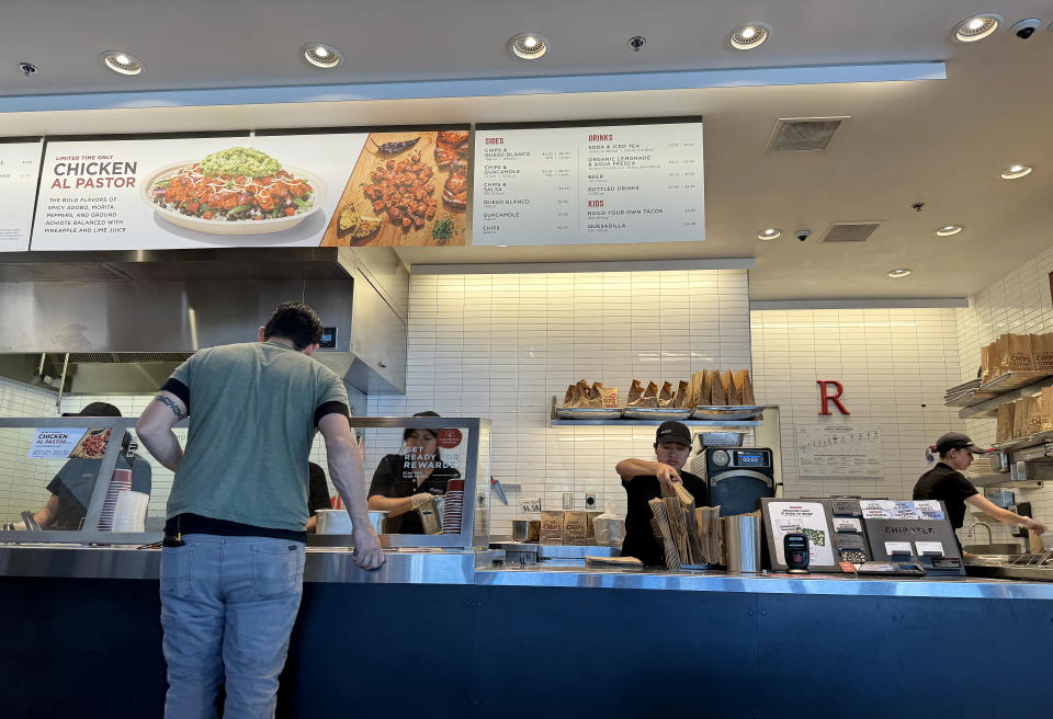 SAN RAFAEL, CALIFORNIA - APRIL 01: Workers help a customer at a Chipotle restaurant on April 01, 2024 in San Rafael, California. A new minimum wage law went into effect in California today that calls for fast food restaurants with at least 60 locations nationwide to pay employees a minimum of $20 per hour at their stores in California. (Photo by Justin Sullivan/Getty Images)