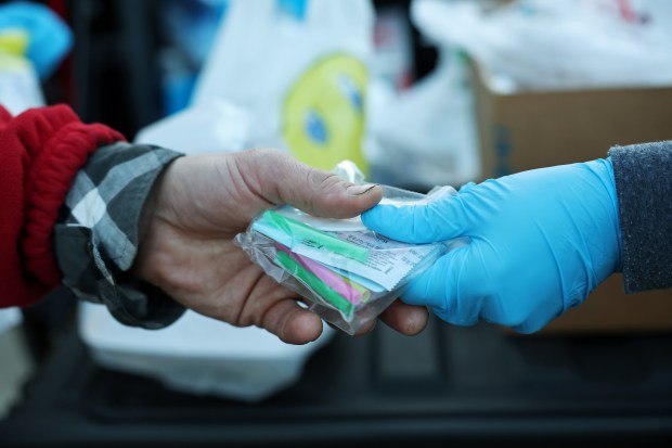 Puerto Rico Project Director Melissa Hernandez, right, hands an unhoused man drug use harm reduction supplies near a tent encampment in the 3000 block of West Chicago Avenue, April 19, 2024, in Chicago. (John J. Kim/Chicago Tribune)