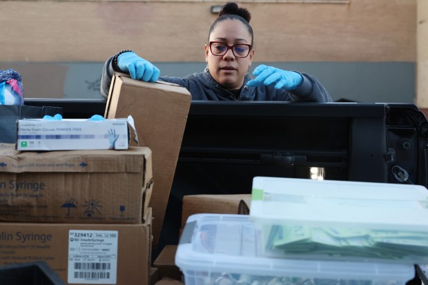 Puerto Rico Project Director Melissa Hernandez retrieves a case of syringes to give to an unhoused couple, along with other drug use harm reduction supplies, near a tent encampment in the 3000 block of West Chicago Avenue, April 19, 2024, in Chicago. (John J. Kim/Chicago Tribune)