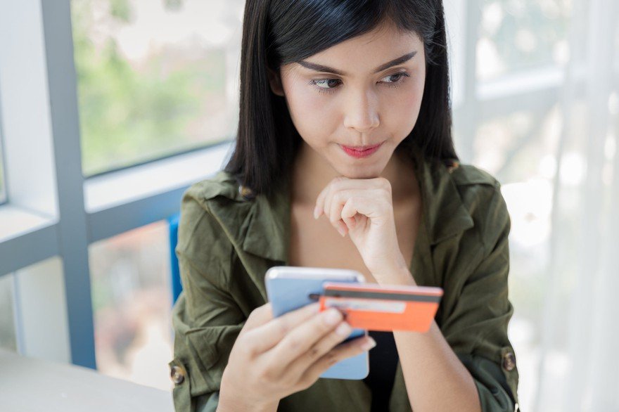 Someone holding a smartphone and credit card.