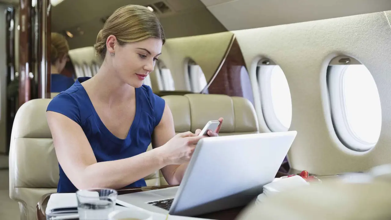 Young businesswoman using smartphone in airplane.