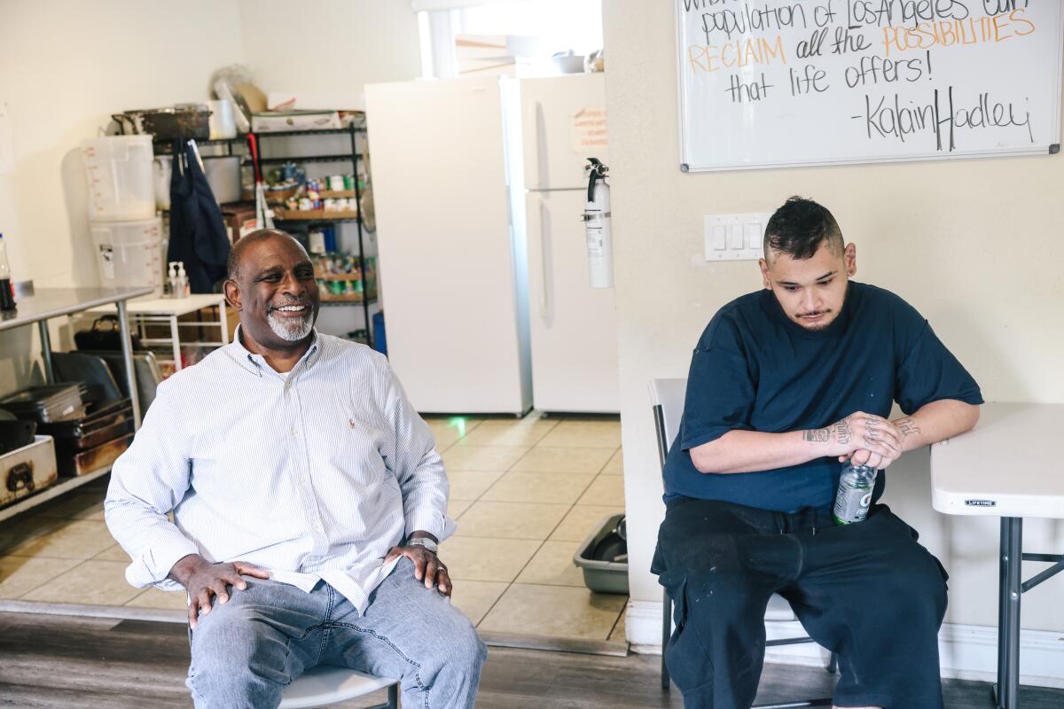 Kalain Hadley, left, smiles as he and another resident sit near a kitchenette in a transitional home