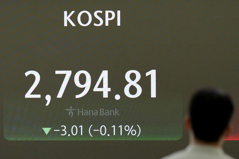 A currency trader walks by the screen showing the Korea Composite Stock Price Index (KOSPI), at a foreign exchange dealing room in Seoul, South Korea, Monday, July 1, 2024. (AP Photo/Lee Jin-man)