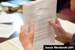 Sister Barbara McCracken looks through prior resolutions filed against various corporations, including Alphabet, Meta, Netflix and Chevron, at the Mount St. Scholastica Benedictine monastery in Atchison, Kan., Tuesday, July 16, 2024. (AP Photo/Jessie Wardarski)