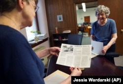 Benedictine sisters, Rose Marie Stallbaumer, left, and Barbara McCracken, right, look through corporate resolution archives and newspaper clippings at the Mount St. Scholastica monastery in Atchison, Kan., Tuesday, July 16, 2024. (AP Photo/Jessie Wardarski)