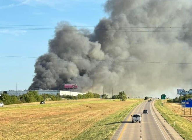 Plumes of smoke drift over Interstate 35 from a fire at the former Dollar Tree distribution center in Marietta, Oklahoma, on Friday morning.