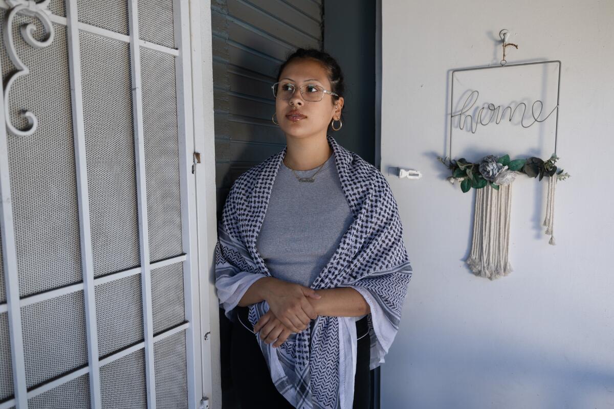 A woman stands outside the door of a house 