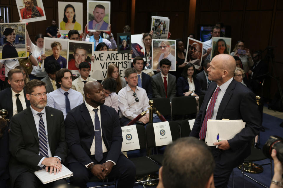 Relatives of Boeing airplane crash victims demonstrate as Boeing President and CEO Dave Calhoun (R) arrives to testify during a Senate Homeland Security and Governmental Affairs Committee Investigations Subcommittee hearing to examine 