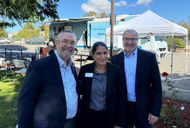 Catholic Charities of Santa Clara County CEO Greg Kepferle, left, RotaCare Bay Area CEO JP Kaur Sahi, center, and Vince Sunzeri of the Rotary Club of San Jose, pose in front of the Rotary Mobile Medical Clinic at a ribbon-cutting ceremony held Thursday, Oct. 17, 2024 at Our Lady of Guadalupe Church in San Jose. (Sal Pizarro/Bay Area News Group)