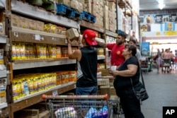 FILE - People buy groceries at a supermarket that accepts 'chachos' currency in La Rioja, Argentina, Sept. 23, 2024.