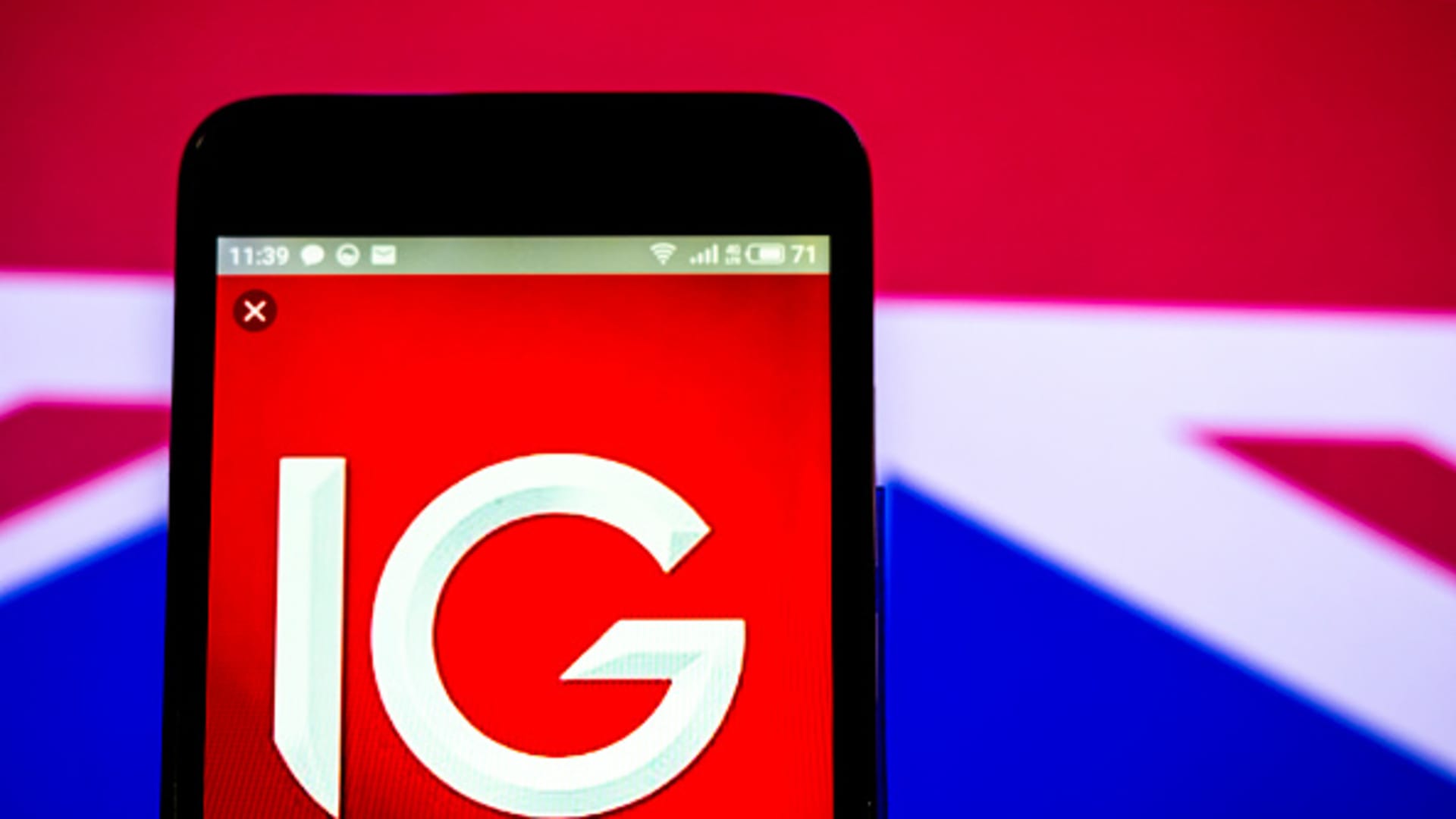 In this photo illustration, the IG Group logo seen displayed on a smartphone.