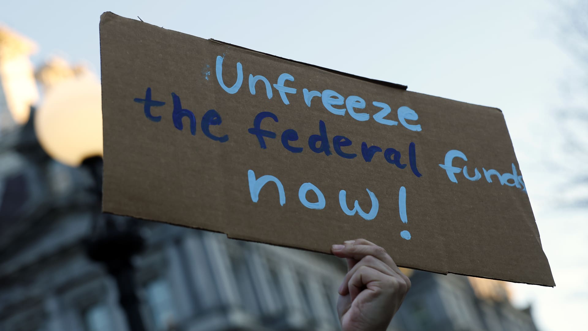 An activist protests against President Donald Trump's plan to stop most federal grants and loans during a rally near the White House on Jan. 28, 2025 in Washington, DC. 