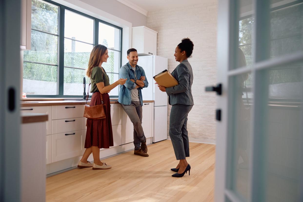 Happy couple talking with real estate agent while buying new home.