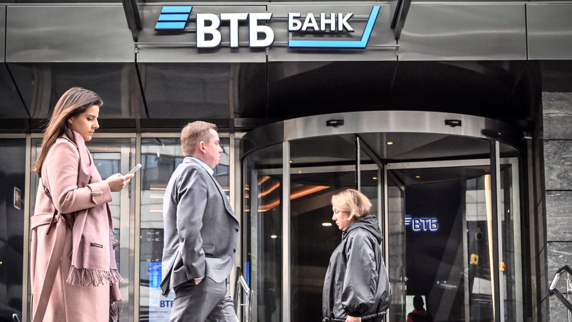 People walk past a branch of Russian VTB bank in Moscow on April 5, 2023. - Russia's second-largest bank, VTB, reported a huge loss amounting to $7.7 billion in 2022 after it was hit hard by Western sanctions over Moscow's offensive in Ukraine.