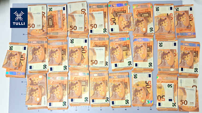 Stacks of counterfeit fifty euro banknotes on a table.