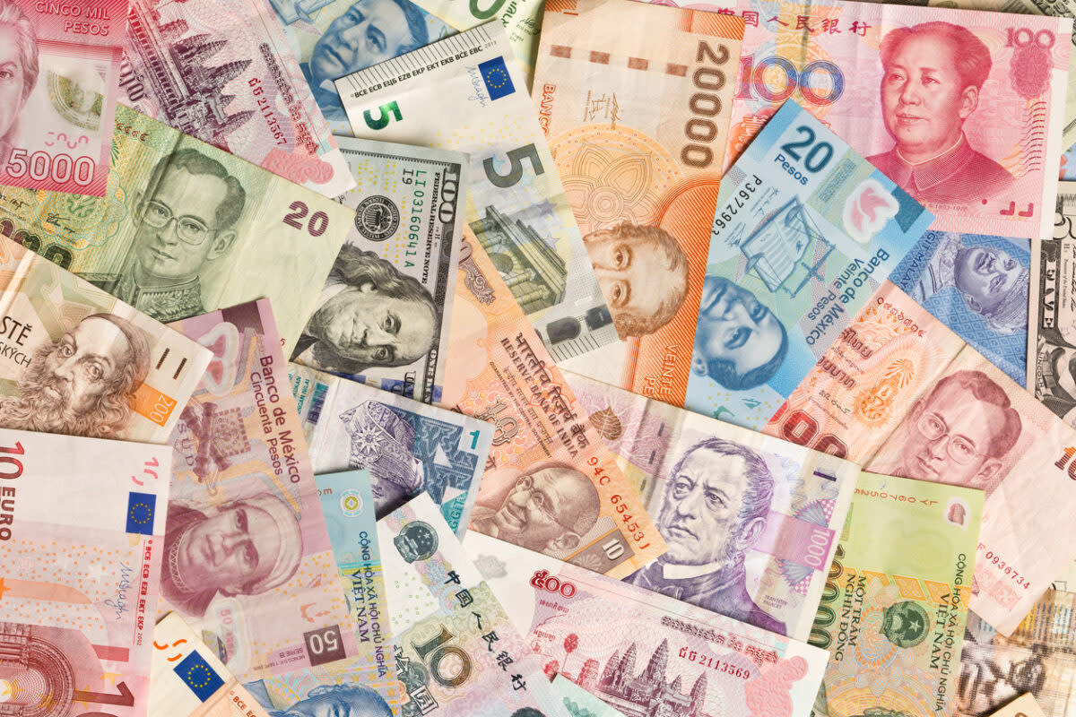 A scattered assortment of international banknotes, featuring currencies from various countries. The notes display different colors, denominations, and portraits, highlighting global diversity in currency design.