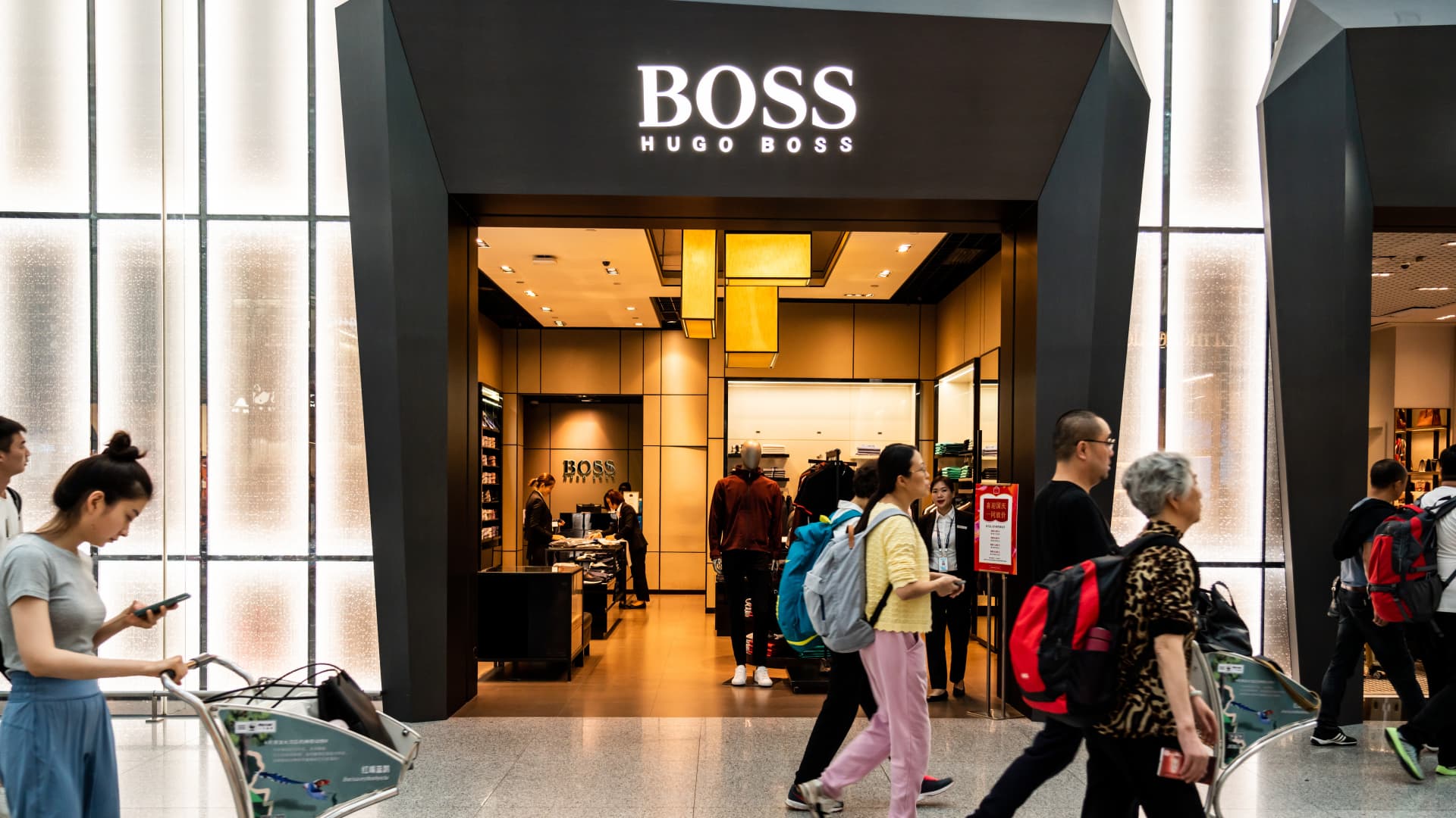 Pedestrians walk past a German luxury fashion house Hugo Boss store in Shenzhen Bao'an International Airport.