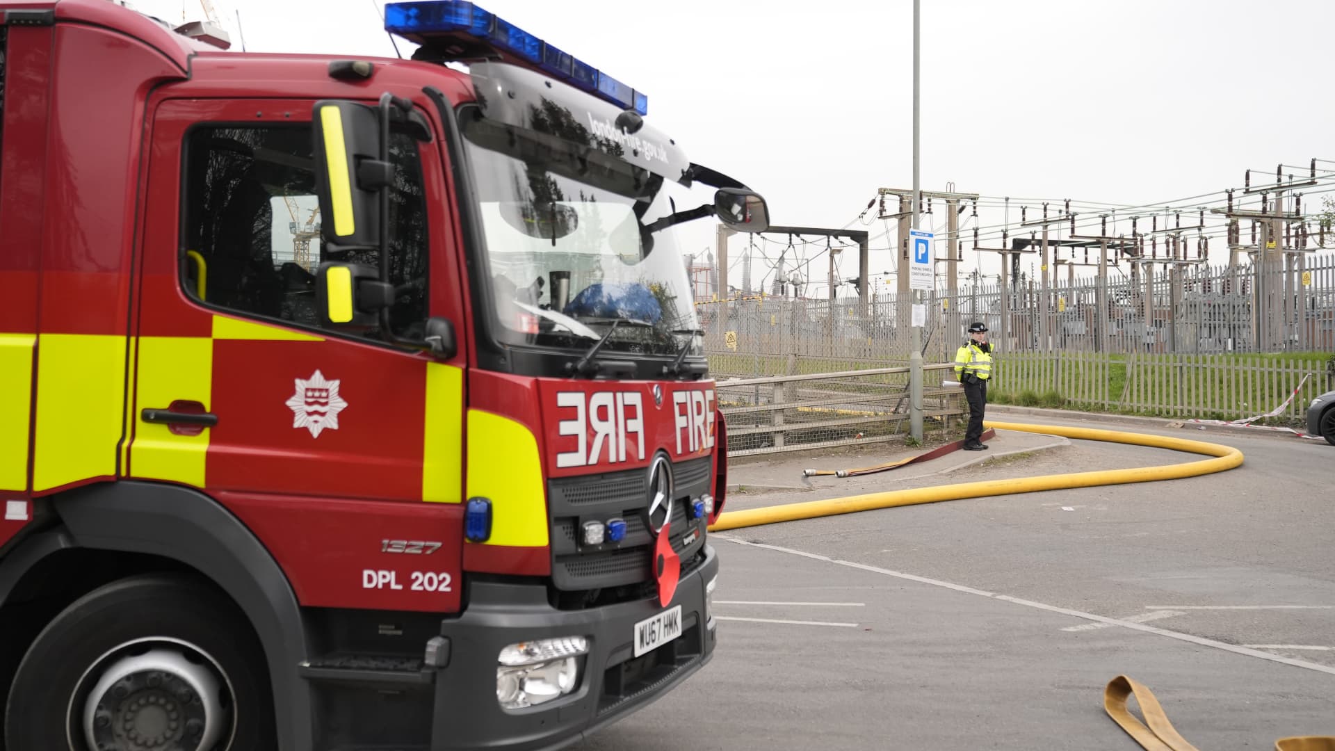 A police officer and firefighters at the North Hyde electrical substation which caught fire. More than 1,300 flights to and from Heathrow Airport will be disrupted on Friday due to the closure of the airport following the fire. Picture date: Friday March 21, 2025. 