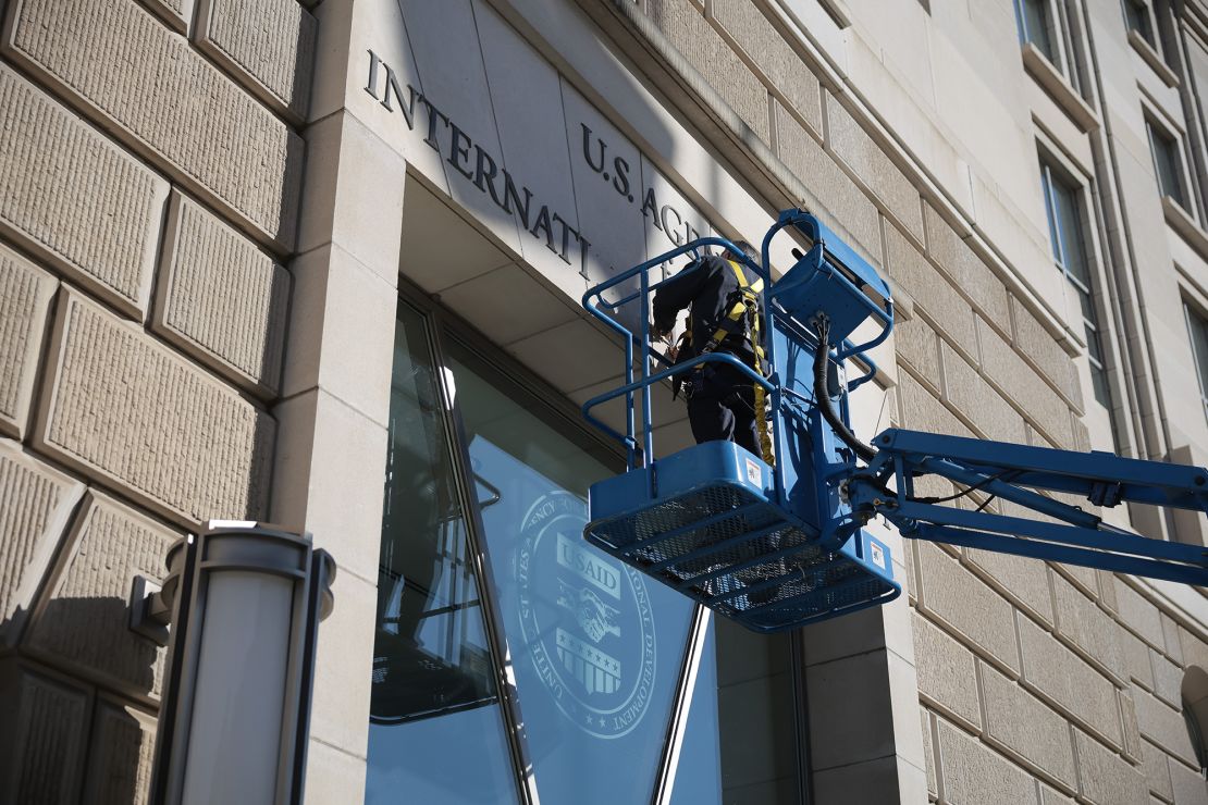 A worker removes the US Agency for International Development sign on their headquarters on February 7, 2025, in Washington, DC.