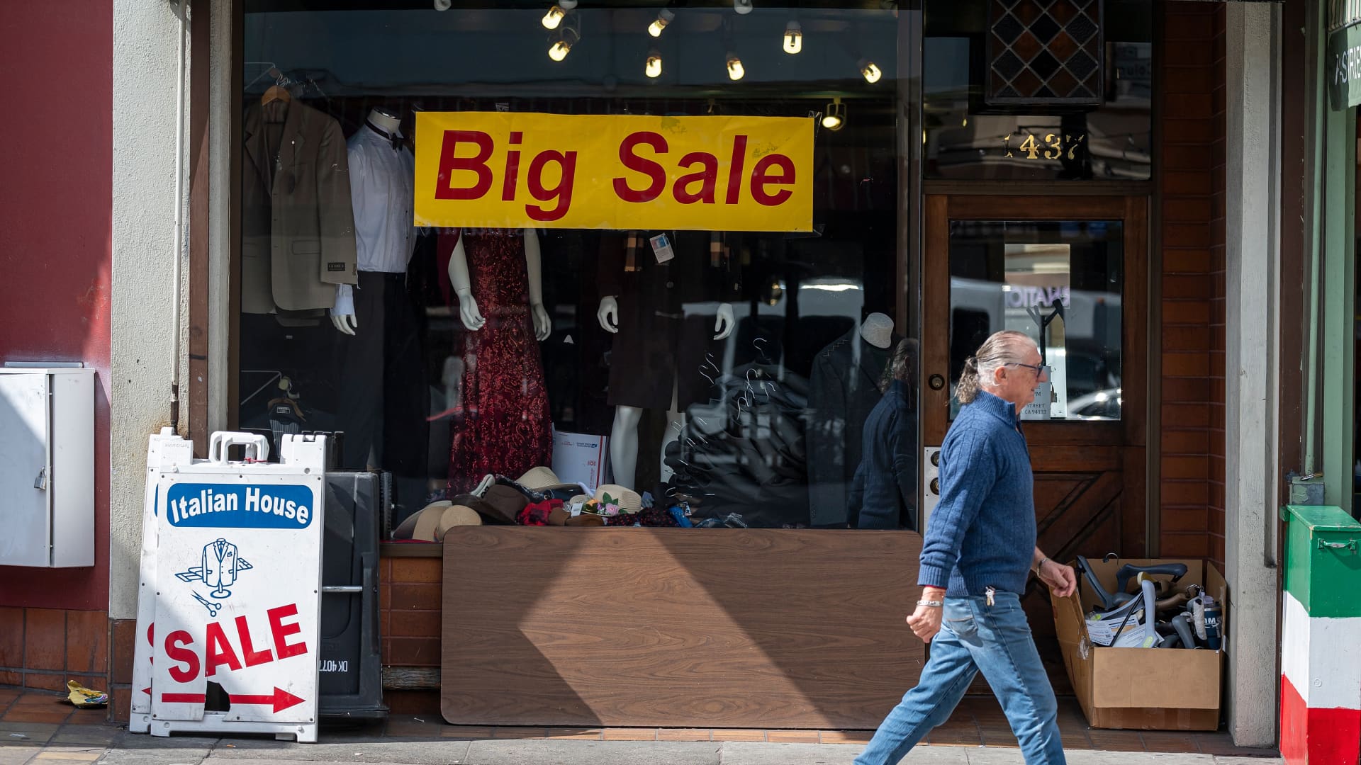 A pedestrian walks past sale signs on a store in the North Beach neighborhood in San Francisco, California, US, on Tuesday, March 11, 2025. 