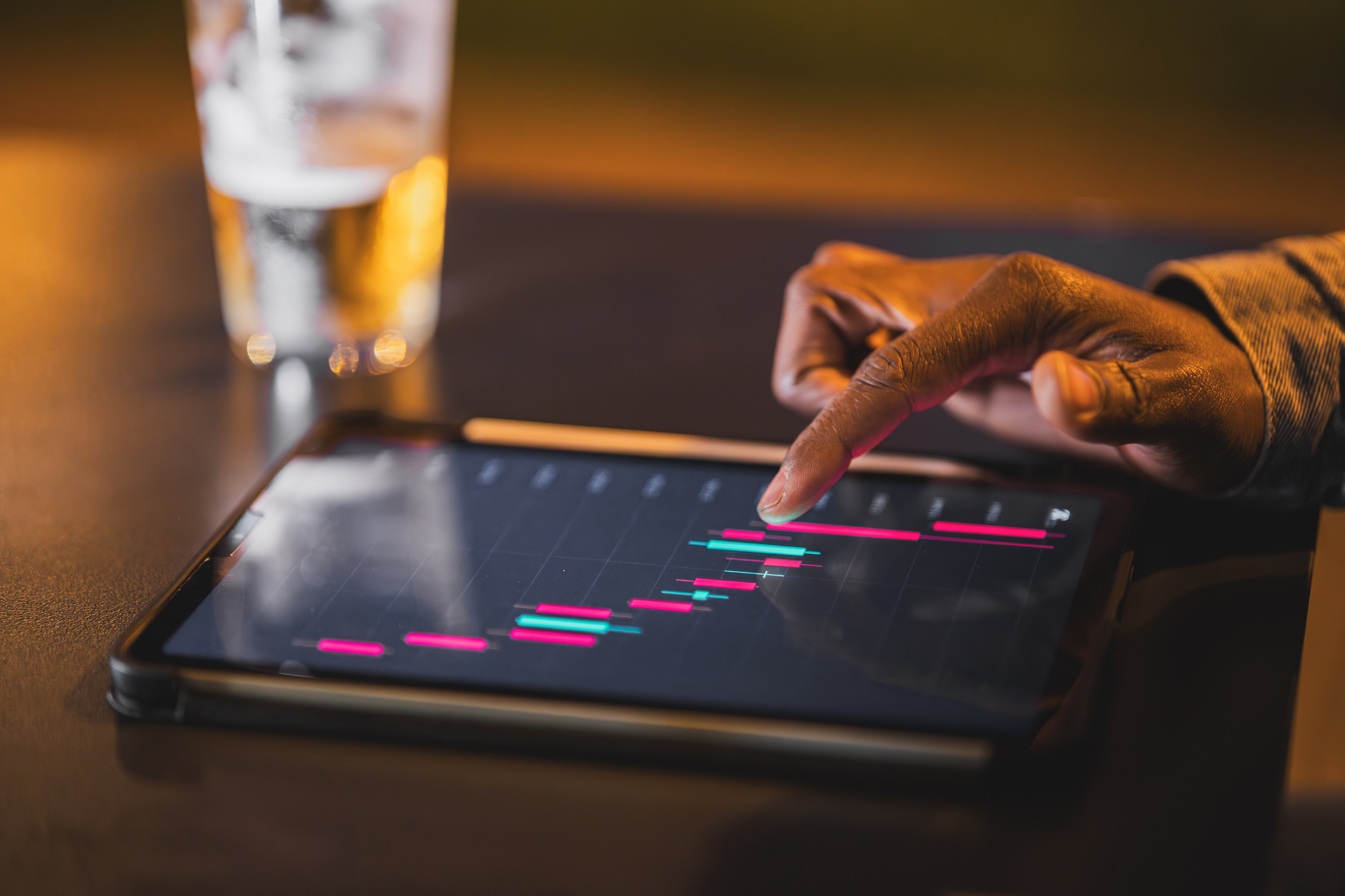 person looking at stock chart with red and green bars on a tablet