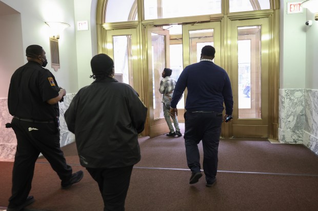 Several security workers usher a man out of the Harold Washington Library Center on April 2, 2025. The man was told he cannot reenter the building for 30 days. (John J. Kim/Chicago Tribune)