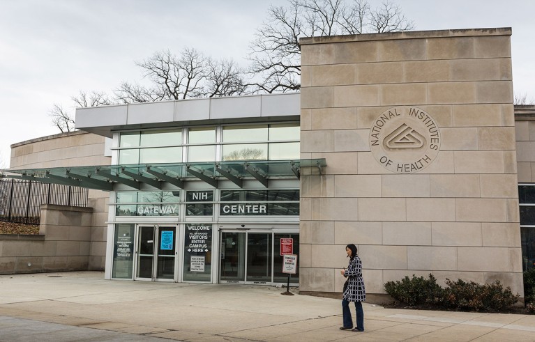 A lone woman pictured outside the entrance to the NIH Campus in Bethesda, Maryland.