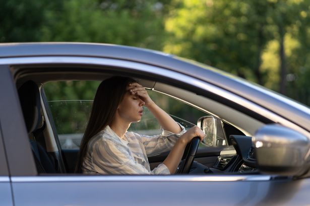 Stressed girl with headache driving car touching forehead with hand