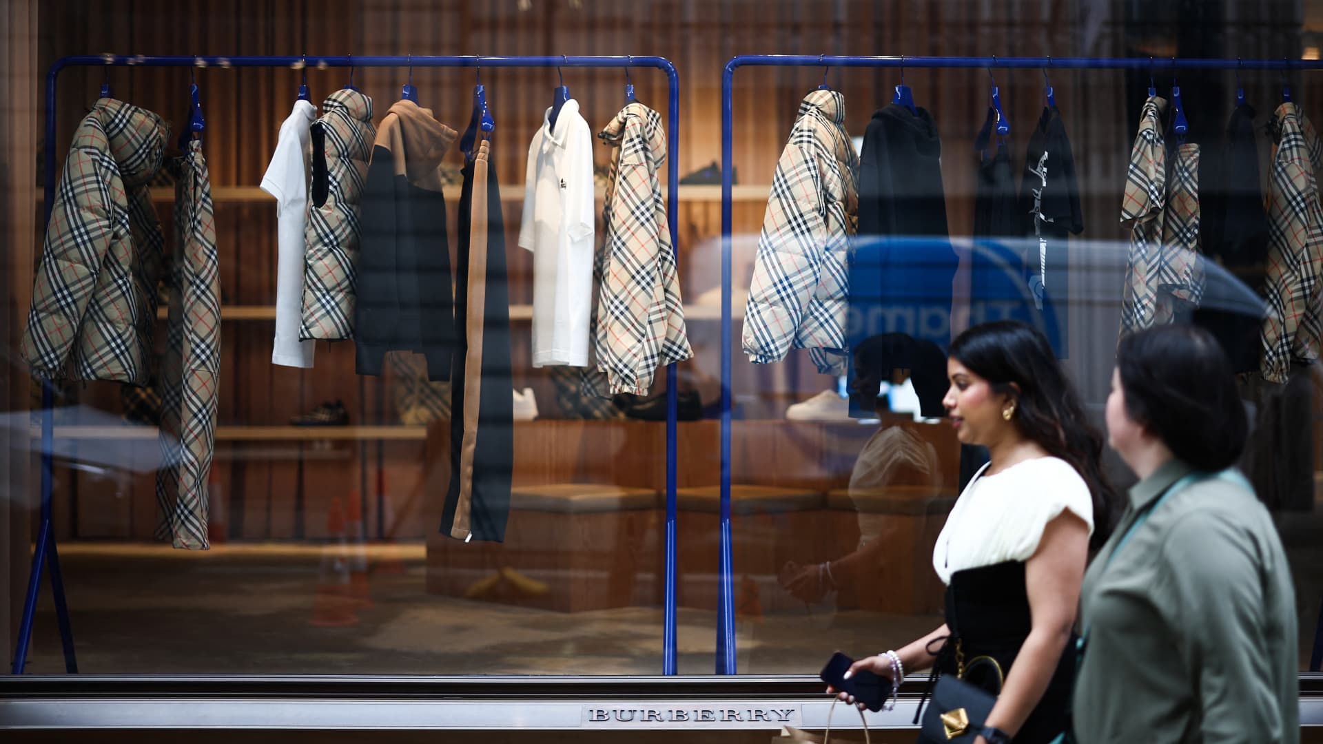 Pedestrians walk past the window display of the store of British fashion label Burberry, in central London, on September 2, 2024.