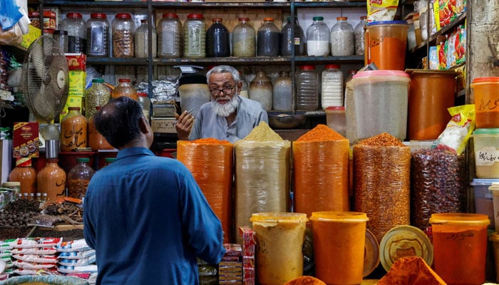A shopkeeper speaks with a customer while selling spices at a market in Karachi, June 11, 2024. — Reuters