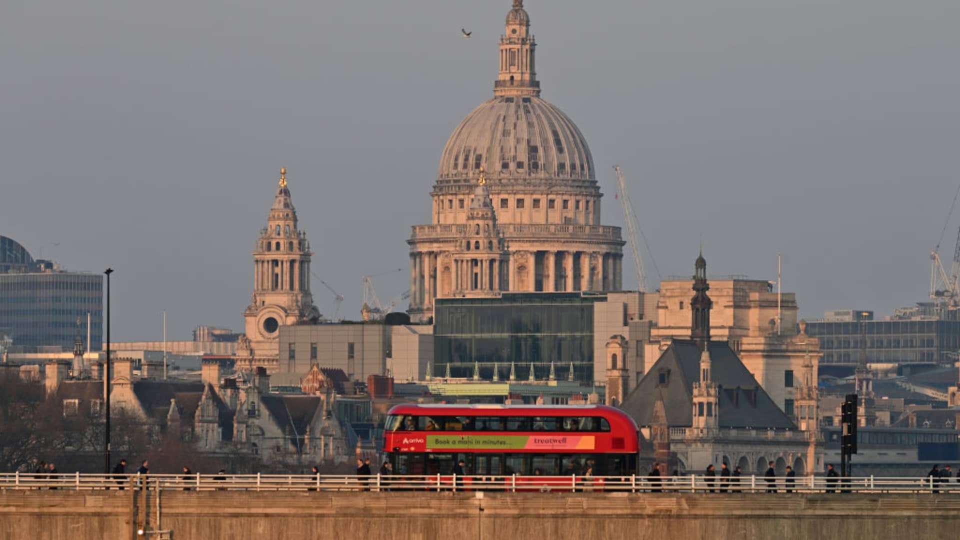 A red London double decker bus passes across Waterloo Bridge in front of St. Paul's Cathedral on March 24, 2025 in London, United Kingdom. 