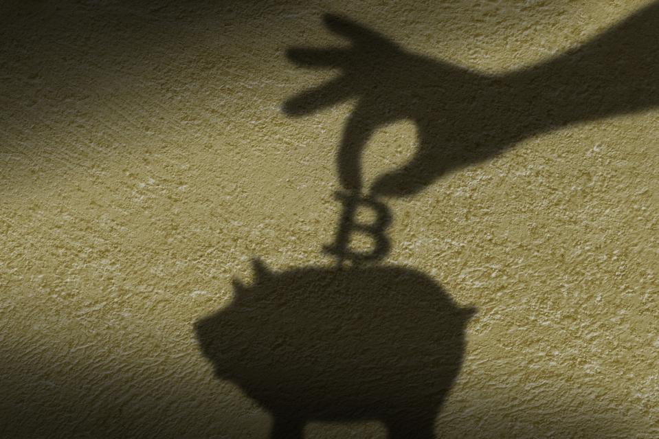 The shadow of hand putting a coin into piggy bank.