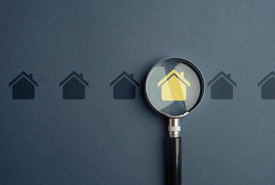 Close-up of magnifying glass with magnifying glass and model home over table
