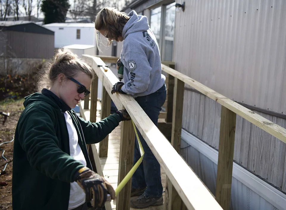 AmeriCorps members rebuild and level a home's walkway that was damaged by Tropical Storm Helene. The members served alongside Asheville Habitat for Humanity until their program was abruptly cut in early April.