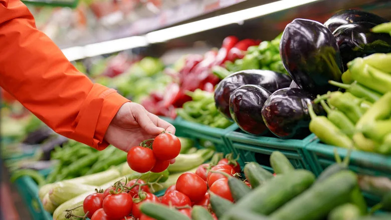 A shopper picking out fresh tomatoes