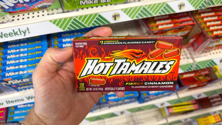 A hand holding a box of overpriced dollar store candy