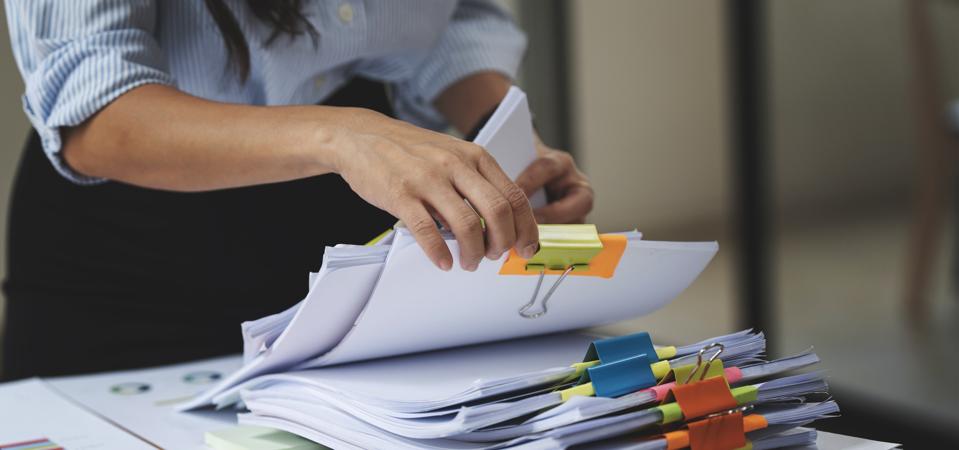 Businesswoman hands working in Stacks of paper files for searching and checking unfinished document achieves on folders papers