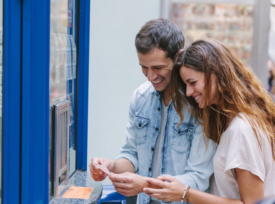 Two people smile while buying lottery tickets.