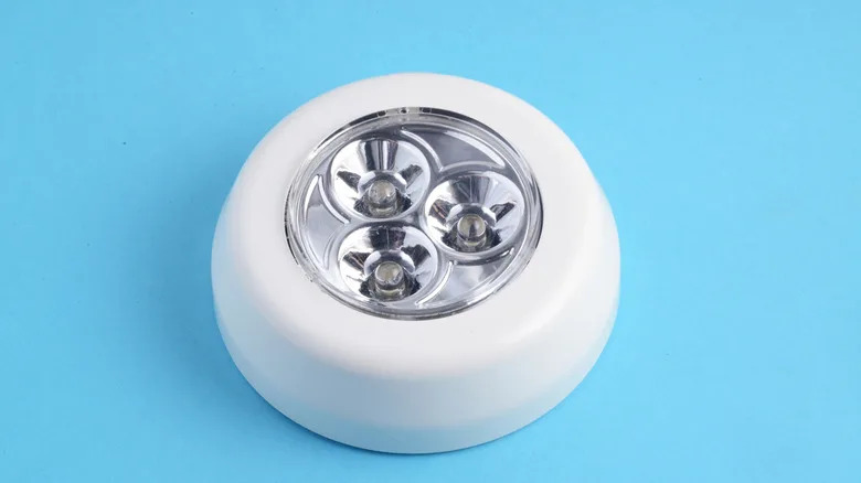 A round LED push light sits on a blue background