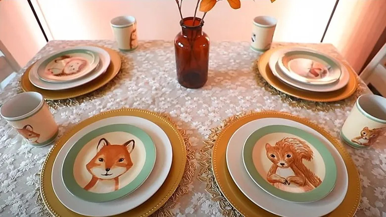 A collection of Dollar Tree critter plates and cups set on a table with a lace cloth