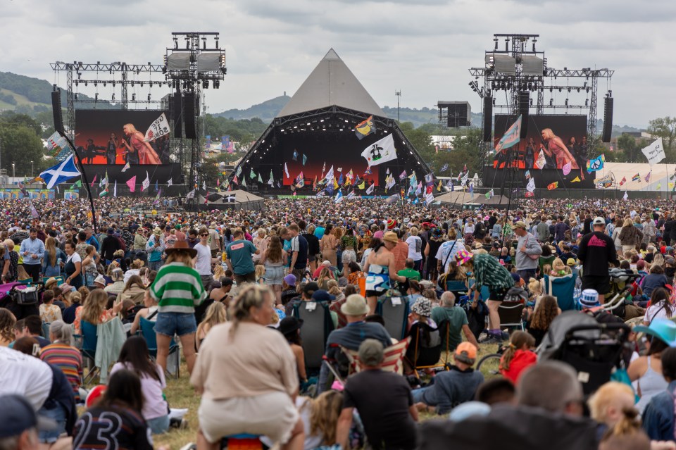 A large crowd gathers in front of the main Pyramid Stage at the Glastonbury Festival.