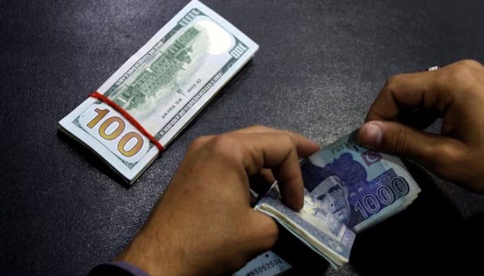 A currency trader counts Pakistani rupee notes as he prepares an exchange of US dollars in Islamabad. — Reuters/File