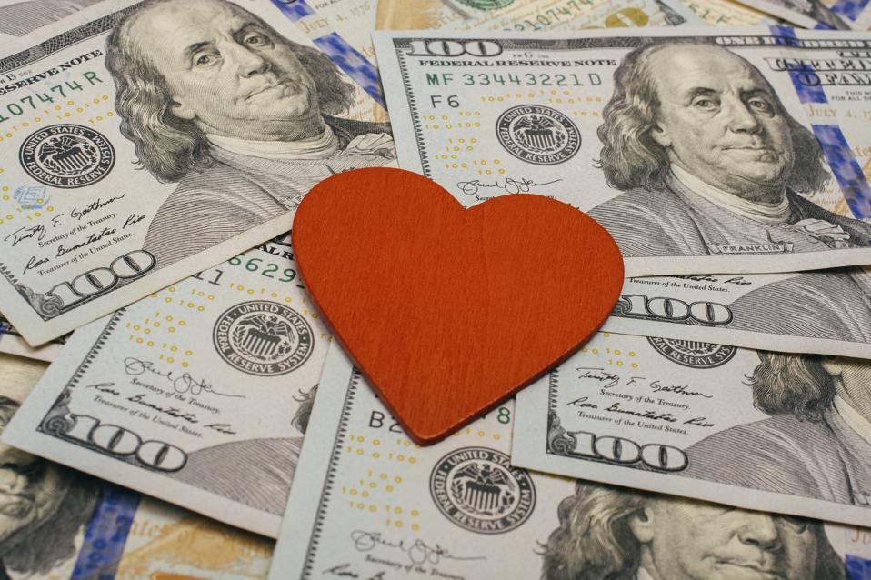 Red heart lies on dollar bills. Concept of selling love for money